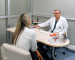 Dr. Carlos Paternina, especialista en uroginecología, brindando asesoría personalizada a una paciente sobre cirugía íntima femenina en su consultorio.
