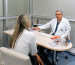 Dr. Carlos Paternina, especialista en uroginecología, brindando asesoría personalizada a una paciente sobre cirugía íntima femenina en su consultorio.