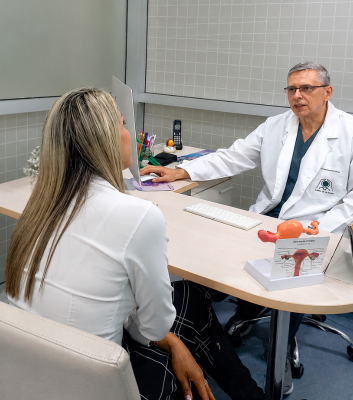 Dr. Carlos Paternina, especialista en uroginecología, brindando asesoría personalizada a una paciente sobre cirugía íntima femenina en su consultorio.